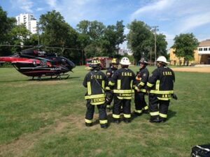 Several firefighters gather near a helicopter that says "Air Care" on the side.