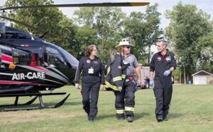A firefighter with two air medics and a helicopter that says "Air Care" on the side.