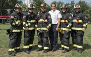 Several firefighters in full gear standing in a field, posed for a photo