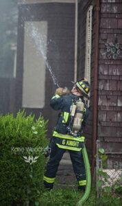 Firefighter/Medic Gary Knight spraying water on a house fire