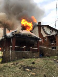 A brick house with flames and smoke coming from the roof