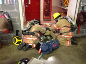 Fire Department training, two firefighters see to a person down on the ground during a training exercise