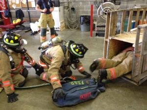 Fire department training inside with wooden props forcing firefighters to crawl and climb across the ground